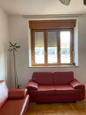a red couch in a living room with a window at Heart of the city big 1BR on Independence square in Podgorica