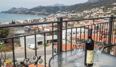 a table with two glasses of wine on a balcony at Lotos - stan 421 L2 in Dobra Voda