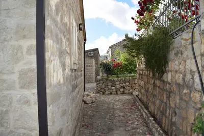 an alleyway in an old stone building with flowers at Unique stone apartment Villa M in Budva