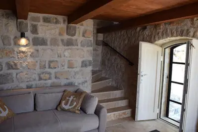 a living room with a couch and a stone wall at Unique stone apartment Villa M in Budva
