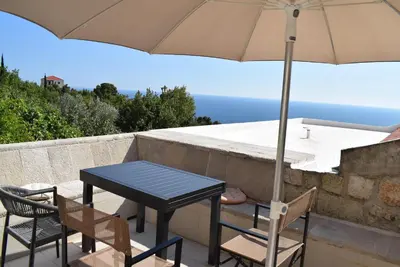 a table and chairs and an umbrella on a balcony at Unique stone apartment Villa M in Budva