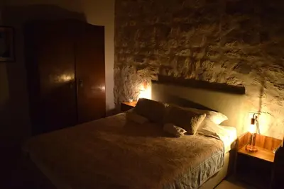 a bedroom with a large bed with a stone wall at Unique stone apartment Villa M in Budva