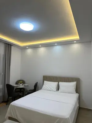 a bedroom with a white bed and a table at Garsonjera u centru Budve in Budva