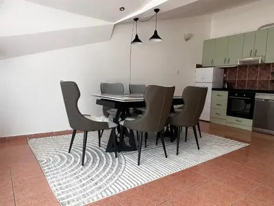a kitchen with a dining table and chairs on a rug at Apartment Zevs 5 in Budva