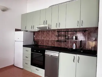 a kitchen with white cabinets and a black counter top at Apartment Zevs 5 in Budva