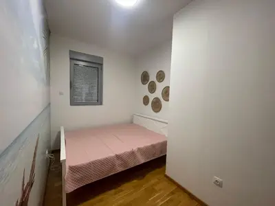 a small bedroom with a pink bed and a window at Apartman Zlatni dan - zgrada Idea - Bečići in Becici