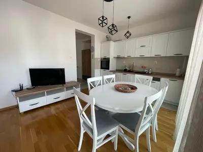 a kitchen and dining room with a white table and chairs at Apartman Zlatni dan - zgrada Idea - Bečići in Becici