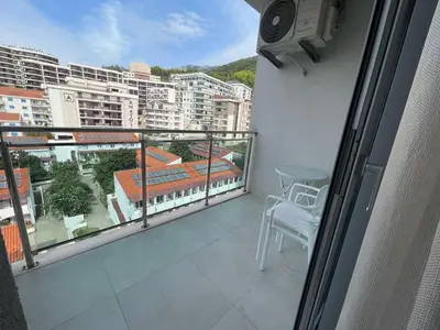 a balcony with a chair and a view of a city at Apartman Zlatni dan - zgrada Idea - Bečići in Becici