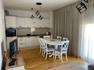 a kitchen with a white table and chairs in a room at Apartman Zlatni dan - zgrada Idea - Bečići in Becici