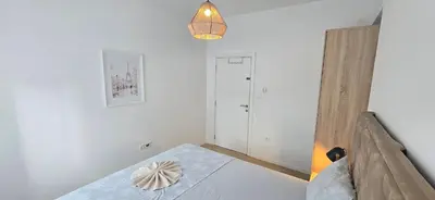 a white bedroom with a bed and a lamp at Apartment Olive Nest in Budva
