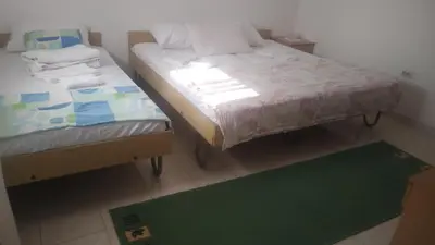 two twin beds in a room with a green rug at Filipova vikendica in Peroči