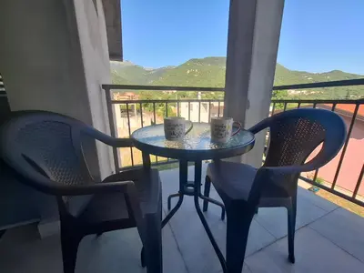 two cups on a table with two chairs on a balcony at Apartman Andjela 2 in Budva