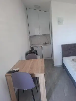 a room with a wooden table and chairs and a bed at Apartman Andjela 2 in Budva