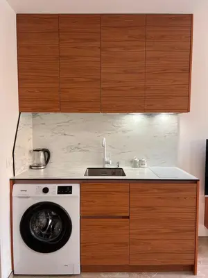 a kitchen with a washing machine and wooden cabinets at Apartmani Vanity Budva in Budva