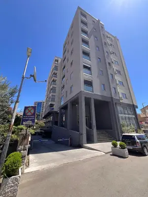 a tall building with a car parked in front of it at Apartmani Vanity Budva in Budva