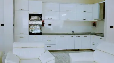 a white kitchen with white cabinets and a white chair at Apartment Matej 2 in Budva
