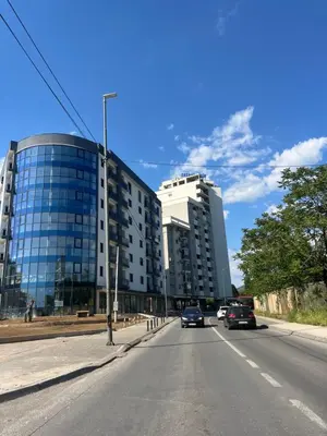 a street with cars driving down a road with buildings at Dora apartment with terrace and parking in Podgorica