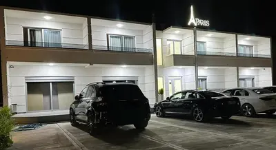 two cars parked in a parking lot in front of a building at Apartments Paris in Donji Štoj