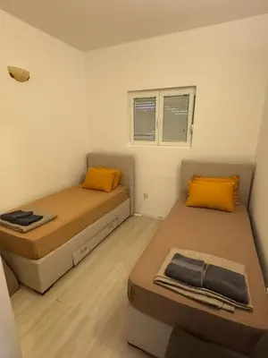 two beds in a small room with yellow pillows at Apartman Itana Budva in Budva