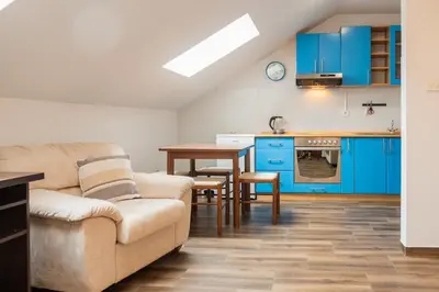 a living room with a couch and a kitchen with blue cabinets at Bay View Apartment in Kotor