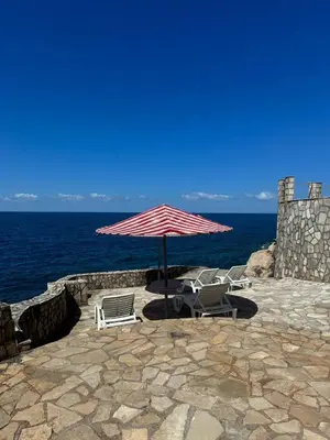 a group of chairs and an umbrella next to the ocean at SF Apartments Lux in Dobra Voda