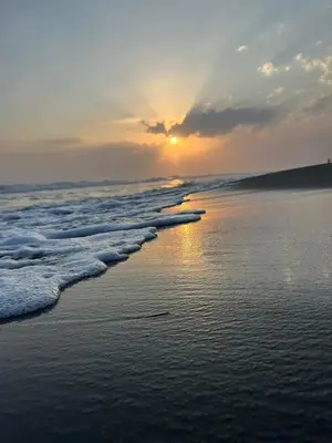 a sunset on the beach with the waves at Villa DUDA rooms in Velika Plaža