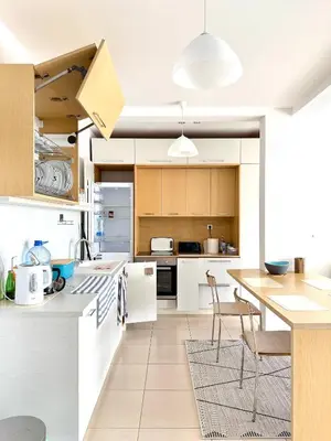 a kitchen with white cabinets and a table and chairs at Hladna Uvala Minimalist 2 Bedroom Apartman in Bar