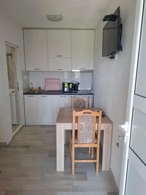 a small kitchen with a wooden table and a chair at Apartman Ratko in Budva
