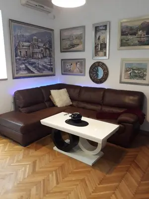 a living room with a brown couch and a white table at Stylish Charm Downtown in Podgorica
