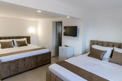 a bedroom with two beds and a tv on the wall at Dea Apartments in Ulcinj
