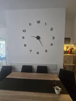 a large clock on a wall above a table at Apartman 44 Bečići in Becici