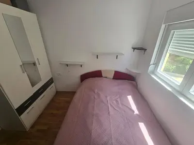 a small bedroom with a pink bed in the corner at Apartman 44 Bečići in Becici