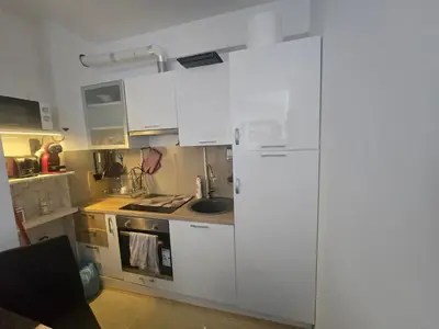 a kitchen with white cabinets and a white refrigerator at Apartman 44 Bečići in Becici