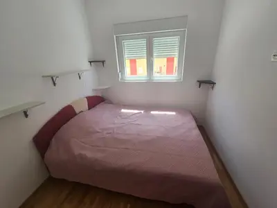 a small bedroom with a bed with a window at Apartman 44 Bečići in Becici