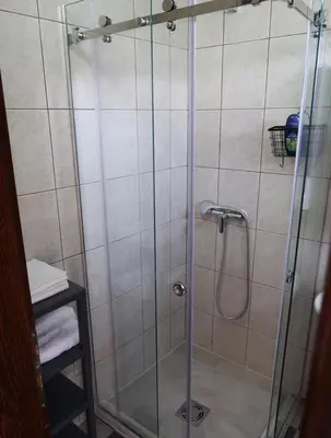 a shower with a glass door in a bathroom at Apartmani Krnić in Tuzi