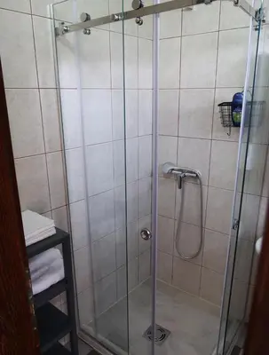 a shower with a glass door in a bathroom at Apartmani Krnić in Tuzi