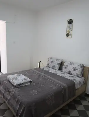 a bedroom with a large bed with gray sheets and pillows at Apartmani Krnić in Tuzi