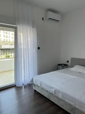 a white bedroom with a bed and a sliding glass door at Lola Guest House in Budva