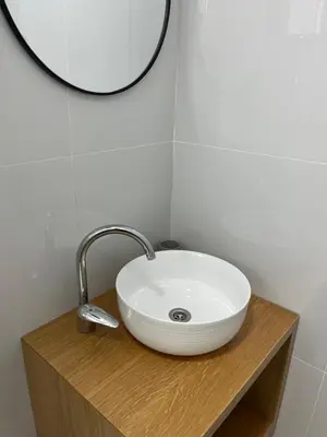 a white sink on a wooden counter with a mirror at Lola Guest House in Budva