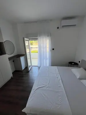 a bedroom with a large white bed and a sliding glass door at Lola Guest House in Budva