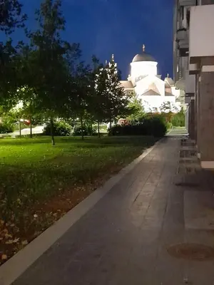 an empty sidewalk in front of a building at night at Apartman Mina in Podgorica