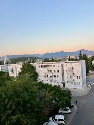 a large white building with cars parked in a parking lot at Cozy Modern Apartment Podgorica in Podgorica