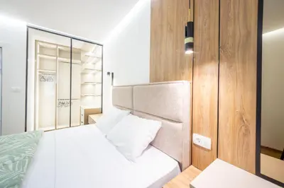 a bedroom with a white bed and a mirror at Fox apartman in Cetinje