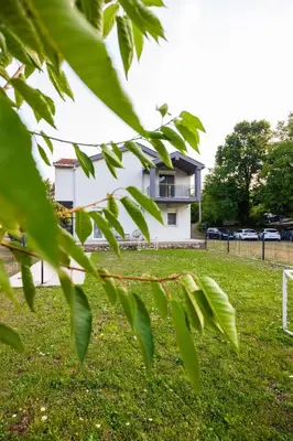 a white building in a field with green leaves at Fox apartman in Cetinje