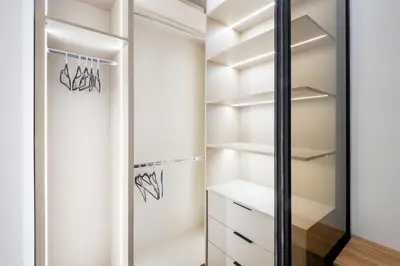 a walk in closet with white cabinets and a glass door at Fox apartman in Cetinje
