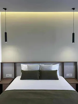 a bedroom with a large bed with two lights above it at Kurti Apartments in Ulcinj