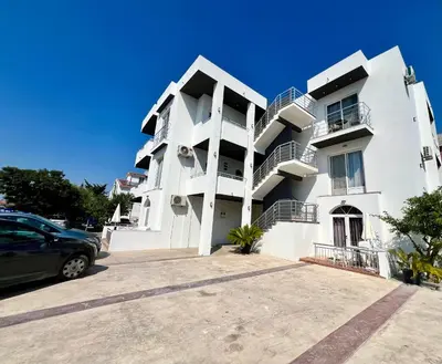 a white apartment building with a car parked in front at Kurti Apartments in Ulcinj