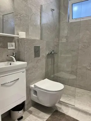 a bathroom with a toilet and a glass shower at Kurti Apartments in Ulcinj