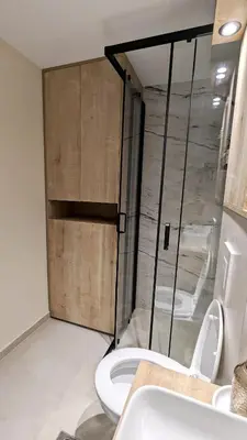 a bathroom with a toilet and a sliding glass door at Cozy apartment in Podgorica in Podgorica