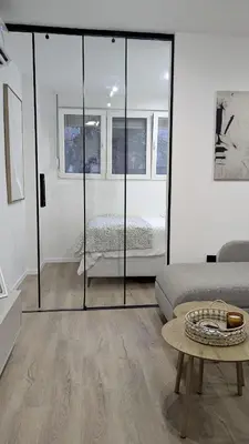 a living room with a glass door with a couch and a bed at Cozy apartment in Podgorica in Podgorica
